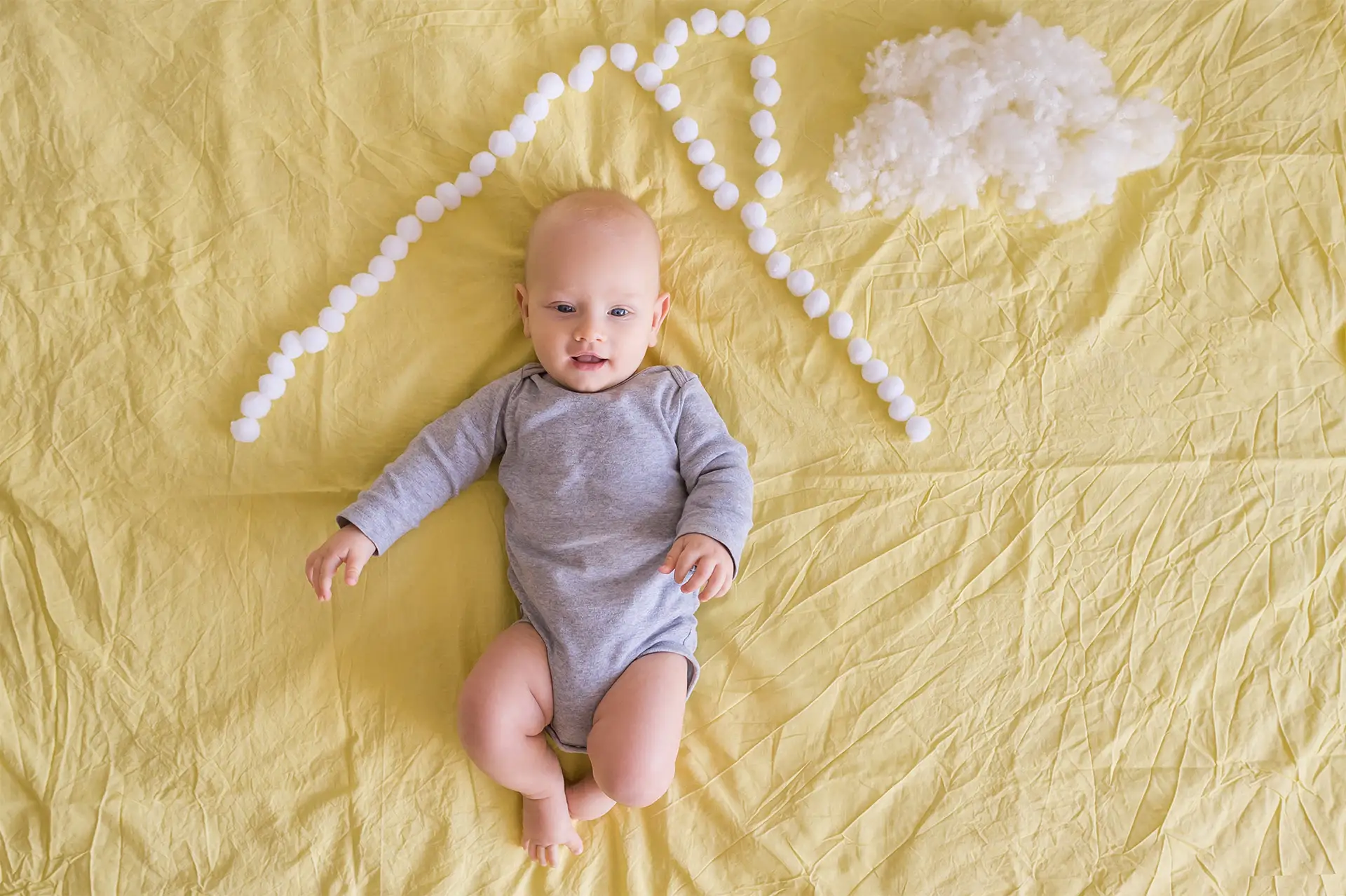 Bambino felice steso sul letto che indossa una tuta in cotone organico