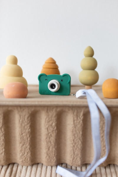 macchina fotografica verde appoggiata su sagoma di cartone con oggetti e nastro azzurro