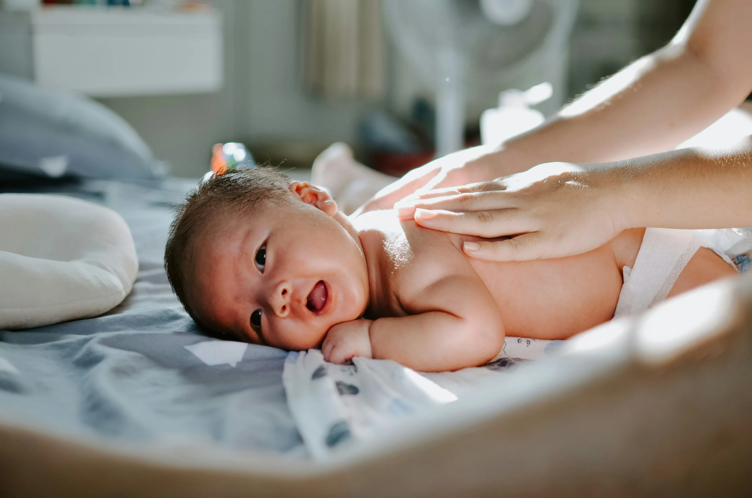 bambino neonato sdraiato su lettino durante una seduta di massaggio